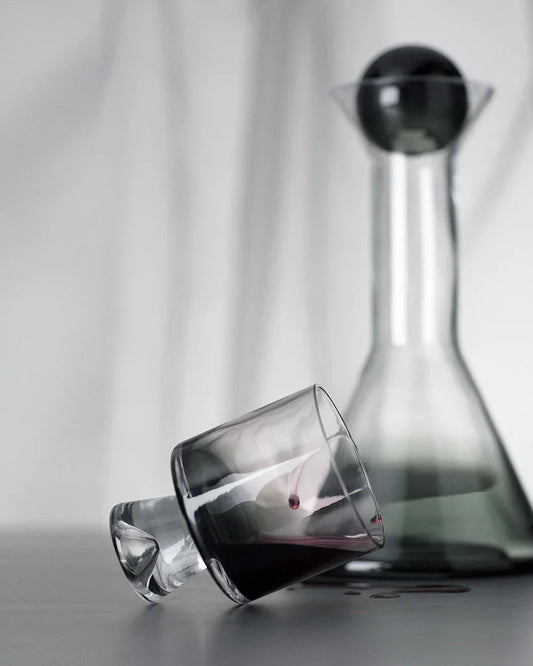 Clear glass decanter and wine glass with red wine on a neutral background